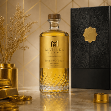 Gold bottle of Matilda Acent with black packaging on a decorative surface.