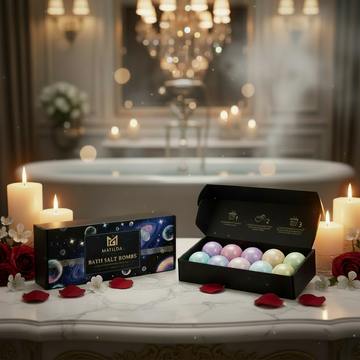 Bath salt bombs in a black box on a bathroom counter with a bathtub and candles in the background.